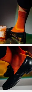 Details von orangefarbenen Baumwollsocken mit breitem Bund und schwarzen Slippern