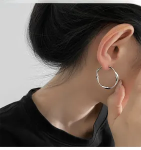 Close-up of geometric twisted silver hoop earrings on a model for a modern look