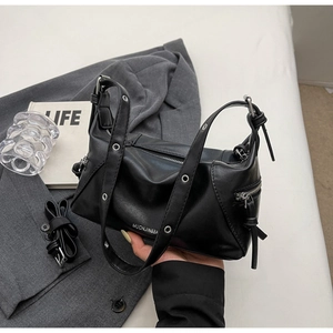 Detail of black leather underarm bag with silver grommets and branded metal zipper texture