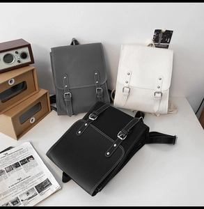 Three minimalist vintage leather backpacks in black, grey, and white with buckle straps