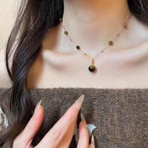 Detailed close-up of tiger eye stone pendant necklace on a model for daily styling