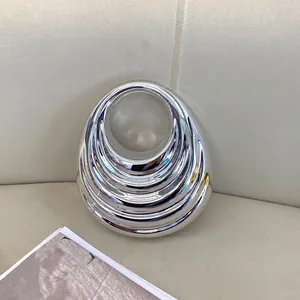 Elegant silver metallic handbag with concentric ripple texture and circular handle