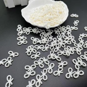Detailed view of white ABS imitation pearl bow beads for DIY necklace and bracelet crafts