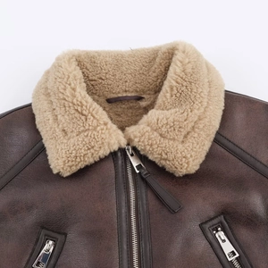 Detail of a brown leather jacket featuring a soft faux fur collar and silver metal zipper
