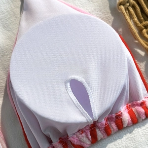 Detail of bikini inner lining with white mesh, round padding inserts and striped trim