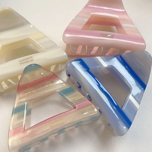 Dettaglio di fermagli per capelli in acetato con strisce colorate e design a triangolo