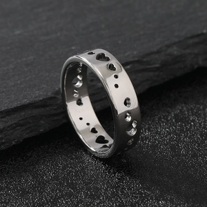 Polished titanium steel ring featuring hollow heart shapes on textured black stone
