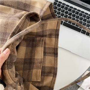 Close-up of brown plaid wool fabric texture and practical front pocket on casual tote bag