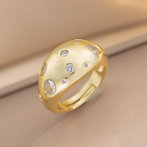 Macro view of a gold-toned dome ring with gypsy-set cubic zirconia and open band