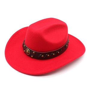 Detail of red wool cowboy hat with studded leather band and vintage metal emblem