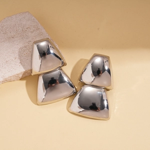 Minimalist geometric trapezoid earrings with silver mirror finish on a stone background