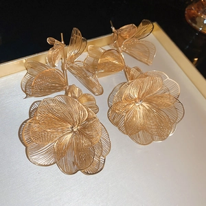 Primo piano di orecchini a fiore in filo dorato intrecciato in un porta gioielli