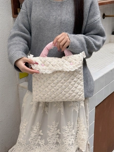 Detail of pink soft handles and lace trim on a white floral quilted laptop sleeve bag