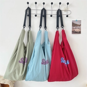 Détail de trois sacs cabas à texture gaufrée en vert foncé, bleu ciel et rouge bordeaux