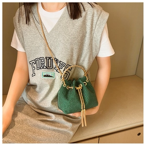 Detail view of dark green rhinestone bucket bag with golden ring handle on a model