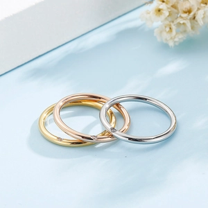 Detail of three slim stackable rings in gold, rose gold, and silver with single diamond