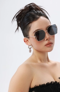 Close-up of luxury irregular oversized sunglasses and silver padlock chain earrings