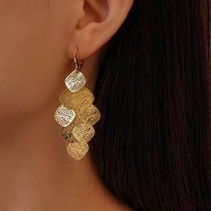 Detailed view of layered gold hollow mesh diamond fringe earrings on model