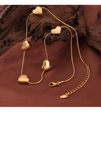 Close-up of golden heart pendant necklace with snake chain on rustic wooden surface