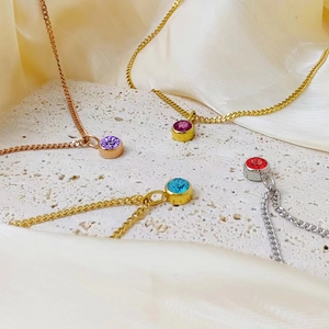 Detail van kleurrijke ronde geboortesteen hangers aan goud en zilver kettingen