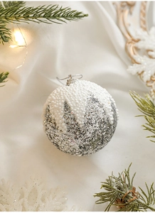 Gros plan d'une boule de Noël argentée à paillettes avec texture de neige en mousse blanche