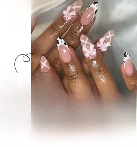 Detail of pink almond press-on nails with 3D bows and french cow print patterns