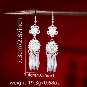Macro detail of silver ethnic tassel earrings with flower pattern and size markings