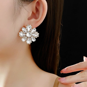 Sparkling crystal flower earrings worn by a model against a black background