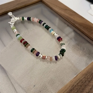 Macro view of colorful natural stone beads and silver lobster clasp on linen fabric