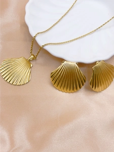 Detailed view of a gold shell jewelry set with a pearl necklace and matching earrings