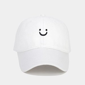 Close-up of white cotton baseball cap featuring black smiley face embroidery detail