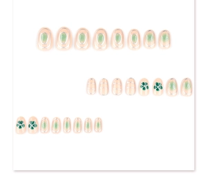 Detail of green blush press-on nails with silver outlines and clover patterns