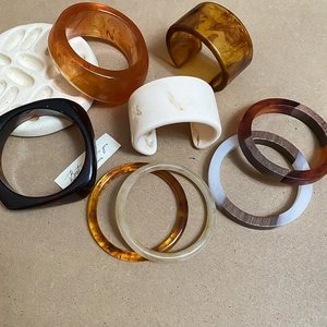 Detailed flat lay of iridescent resin bangles in amber, tortoiseshell, and marble textures