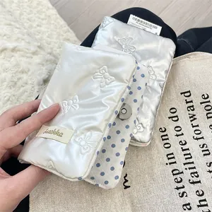 Detail of quilted white satin passport holder with bow pattern and metal magnetic snap