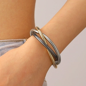 Macro detail of three-strand gold and silver mixed metal coil bracelet on wrist