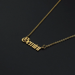 Macro detail of Gemini gothic font pendant on a gold stainless steel necklace chain