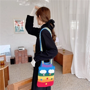 Rainbow knit shoulder bag with 3D cloud detail and colorful pompoms on a model