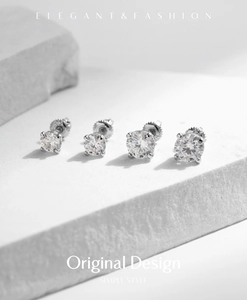 Macro detail of classic 4-prong moissanite stud earrings on elegant textured stone