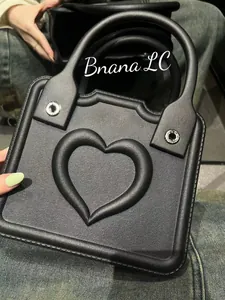 Close-up detail of black leather handbag with embossed heart pattern and silver eyelets