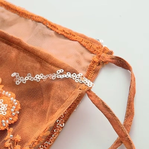 Detailed macro view of orange mesh fabric with shimmering sequins and embroidery