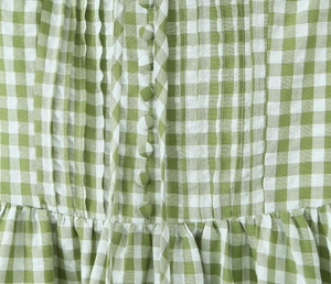 Close-up of green and white gingham cotton dress with ruffle trim and cloth buttons