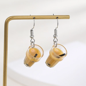 Creative bubble tea cup dangle earrings with pearl details on a gold display stand