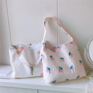 Détail de sacs fourre-tout en seersucker avec imprimés cerise et tulipe et tissu texturé