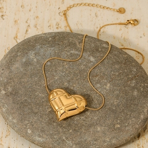 Golden hollow checkered heart pendant necklace on a stone with snake chain