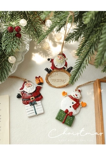 Macro detail of hand-painted Santa and Snowman resin pendants on festive pine branches