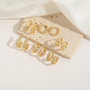 Golden earring set with pearls and zircons displayed on natural beige stone tiles