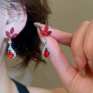 Detailed view of red teardrop earrings with silver finish and sparkling crystals on model