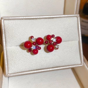 Macro shot of gold plated red cluster stud earrings featuring zircons and red beads