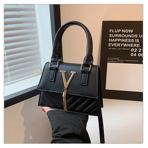 Close-up of black crossbody bag with V-shaped gold hardware and quilted stitch details