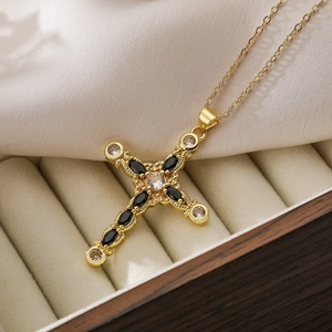 Luxury gold plated cross pendant necklace with black stones on beige suede jewelry box